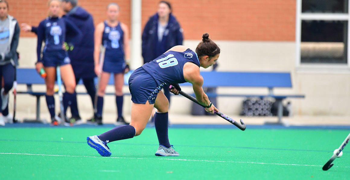 brunette woman wearing jersey number 18 playing field hockey